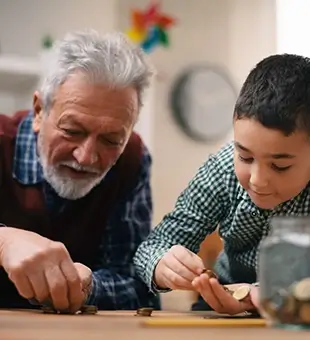 Grandpa and grandson saving money. Grandfather teaching grandchild how to save money.