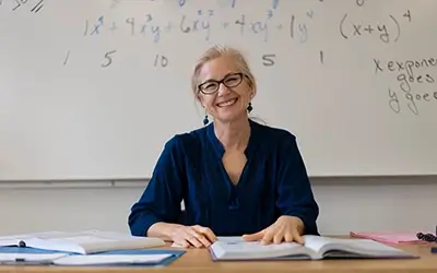 Portrait of high school math teacher sitting at desk working on assignments for students.