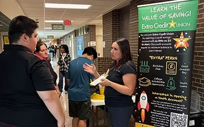 Extra Credit Union speaking with students at a school
